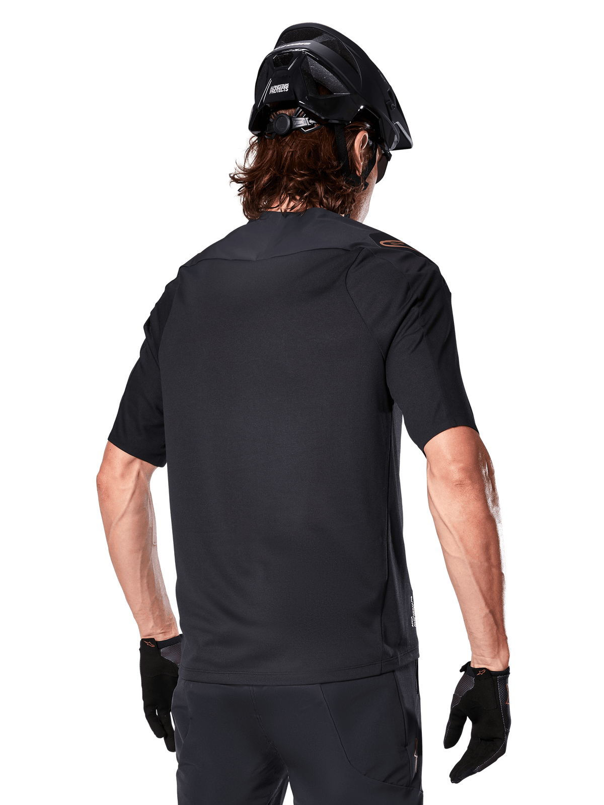 Alpinestars A-Aria Polartec Switch Short Sleeve Jersey, nero, vista posteriore su un rider con casco da mountain bike nero, pantaloncini e guanti neri coordinati, abbigliamento tecnico per mountain bike