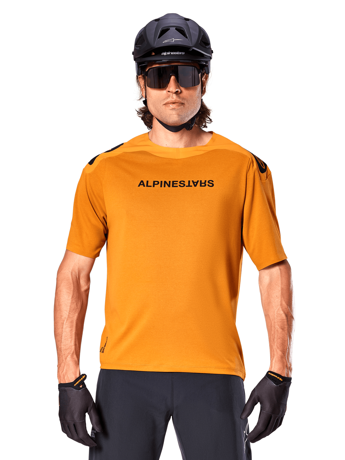 Maglia a maniche corte Alpinestars A-Aria Polartec Switch, oro scuro, ciclista di mountain bike con casco nero e occhiali da sole, abbigliamento tecnico da ciclismo per percorsi MTB