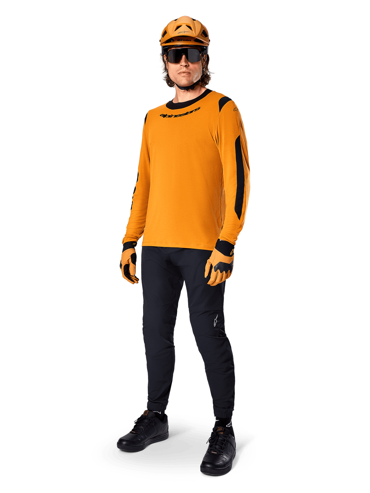 Alpinestars A-Dura Dri Wool Jersey - Manica Lunga, Dark Gold, indossata con casco arancione coordinato, pantaloni da MTB neri e guanti gialli e neri, outfit completo da ciclismo per trail fuoristrada
