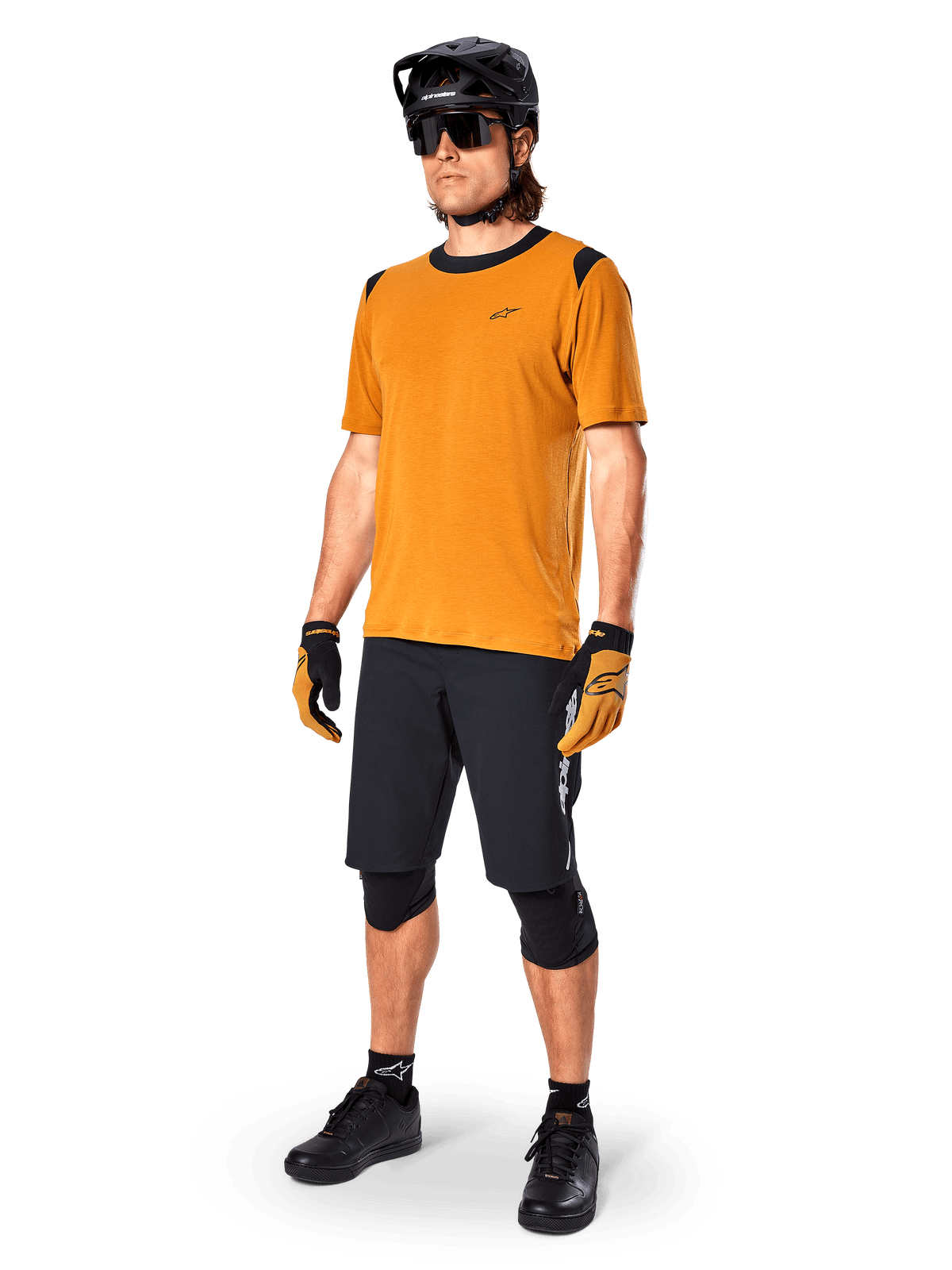 Maglia Alpinestars A-Dura Dri Wool a maniche corte in Dark Gold, maglia da mountain bike con dettagli neri su spalle e colletto, abbinata a pantaloncini da MTB neri, casco nero e occhiali da sole, abbigliamento tecnico da ciclismo fuoristrada