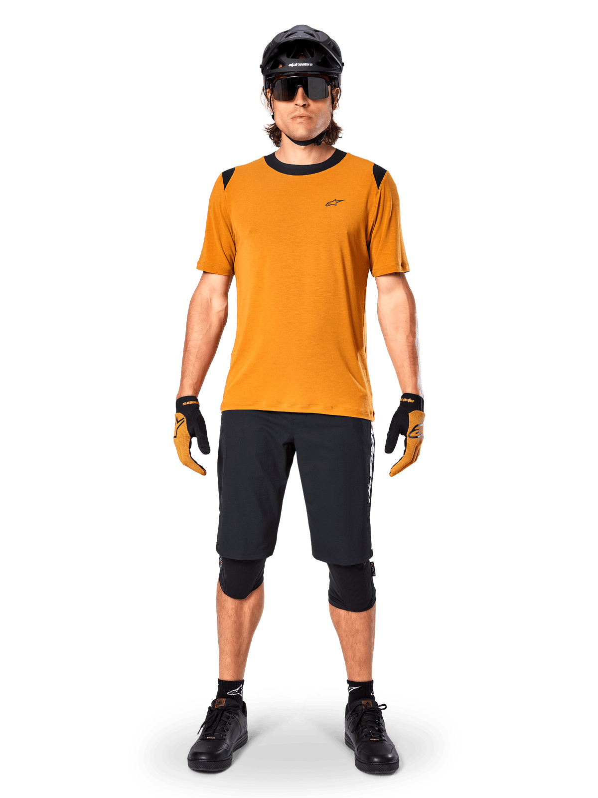 Alpinestars A-Dura Dri Wool Short Sleeve Jersey in Dark Gold, maglia da mountain bike a maniche corte, tessuto giallo senape con colletto e dettagli sulle spalle neri, indossata con pantaloncini neri e protezioni, abbigliamento tecnico da ciclismo per trail