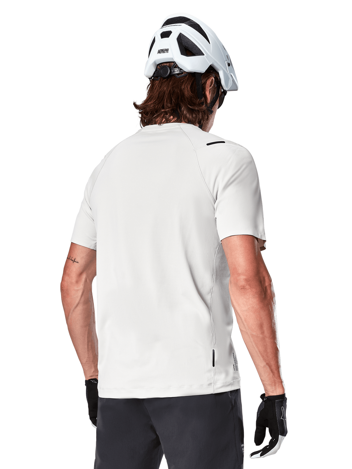 Alpinestars A-Aria Astar Jersey, maniche corte, White Dove, vista posteriore di maglia da mountain bike leggera e traspirante, indossata con casco bianco e guanti da ciclismo neri, con parte posteriore allungata per una maggiore copertura