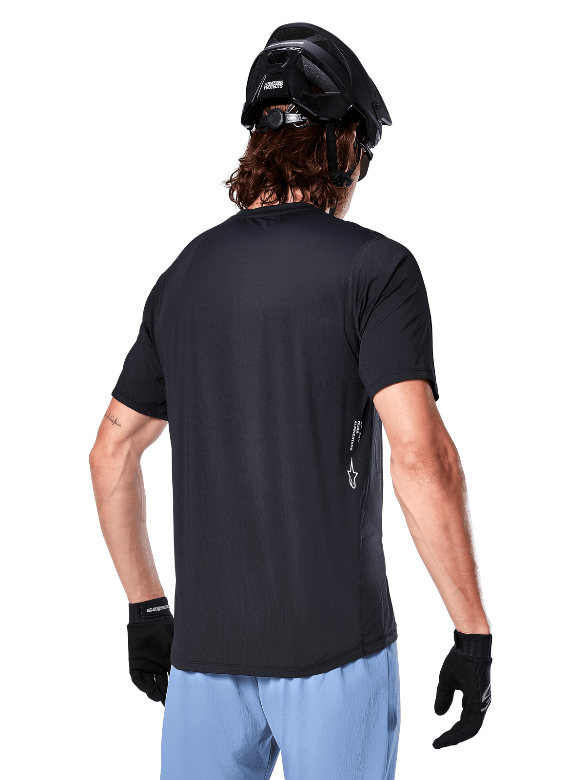 Alpinestars A-Dura Oscar Jersey, maglia da ciclismo a maniche corte, nero, vista posteriore su ciclista, abbinata a pantaloncini azzurri e casco MTB nero, piccolo logo bianco sul lato, abbigliamento tecnico per mountain bike