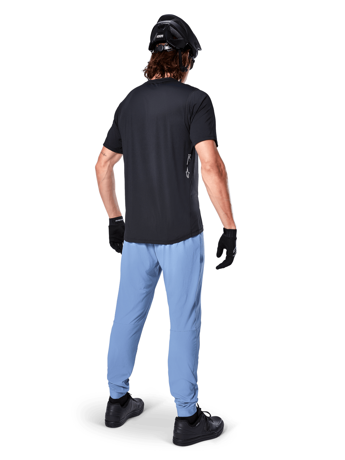 Alpinestars Maglia A-Dura Oscar - Maniche Corte, Nero, vista posteriore di un rider che indossa una maglia da mountain bike nera, abbinata a pantaloni azzurri, casco nero e guanti neri, abbigliamento tecnico da MTB per prestazioni off-road