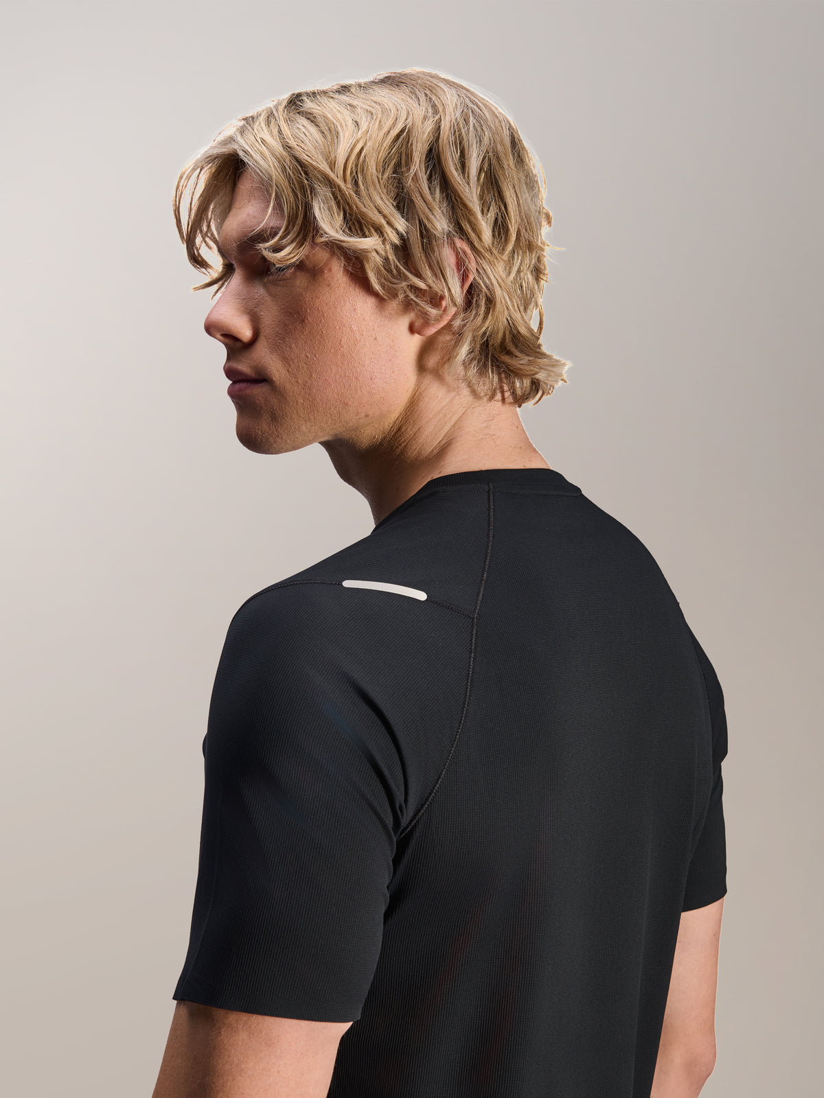 Uomo che indossa la maglia Alpinestars A-Aria Switch, a maniche corte, nero, vista laterale e posteriore che mostra la vestibilità performante e il dettaglio della spalla, abbigliamento da ciclismo MTB leggero e traspirante