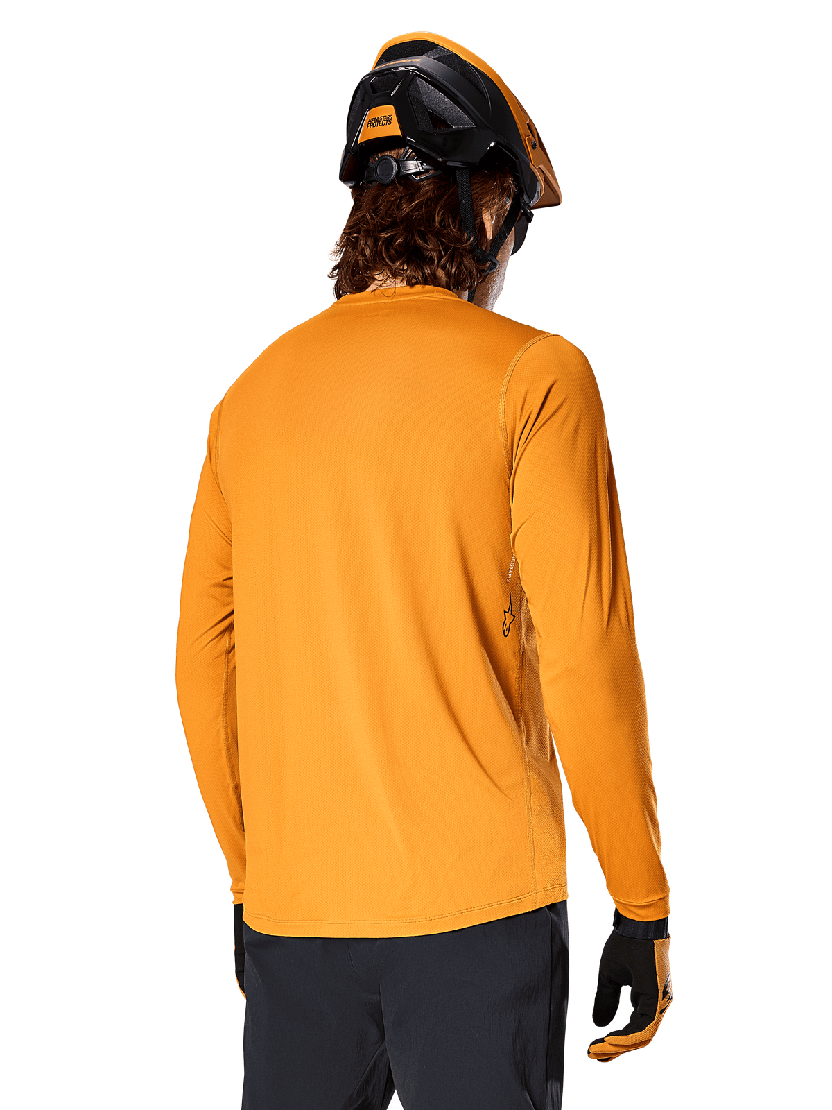 Maglia a maniche lunghe Alpinestars A-Dura Rocker, Dark Gold, vista posteriore del rider con casco da MTB nero e arancione, pantaloni scuri e guanti coordinati, abbigliamento da mountain bike casual ad alte prestazioni