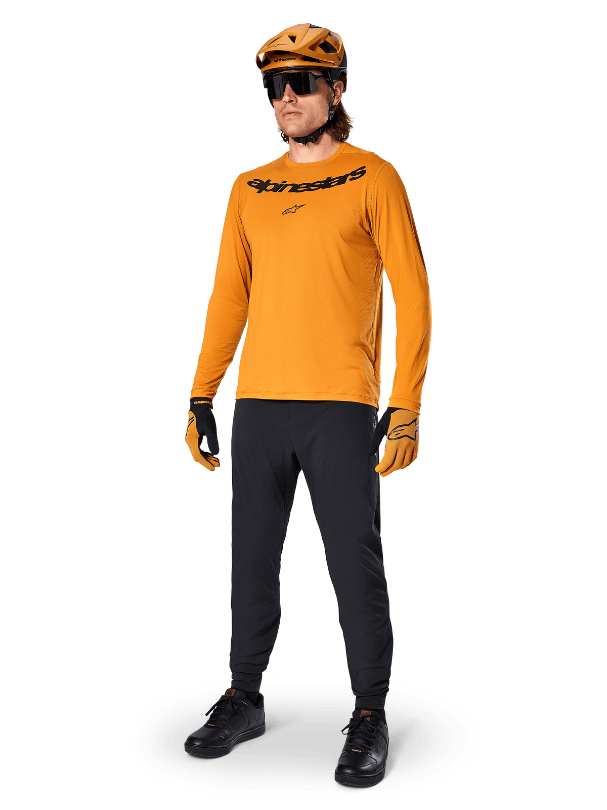 Alpinestars Maglia A-Dura Rocker Long Sleeve, maglia da ciclismo oro scuro, indossata con casco MTB coordinato e pantaloni neri, con logo nero sul petto, abbigliamento tecnico per mountain bike fuoristrada