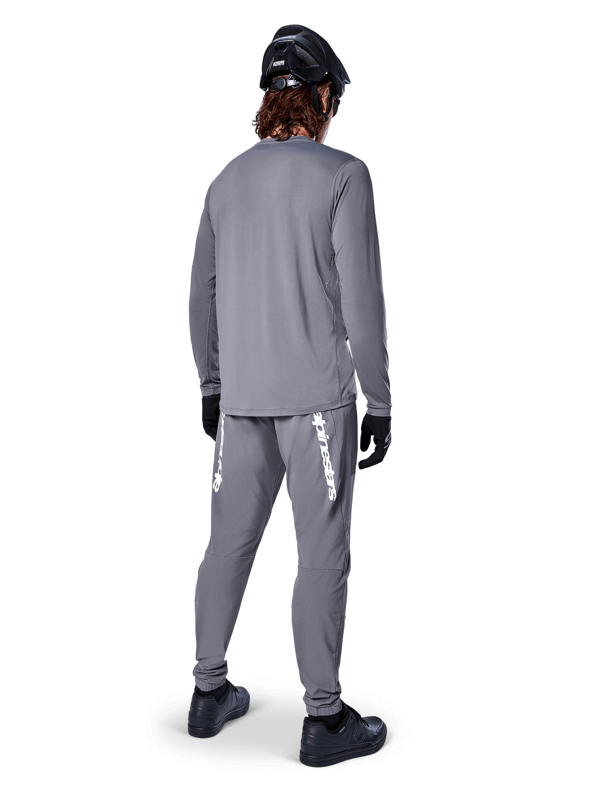 Maglia Alpinestars A-Dura Rocker a maniche lunghe, grigio scuro, vista posteriore del modello con pantaloni da MTB grigi coordinati, casco nero e guanti neri, design professionale per mountain bike