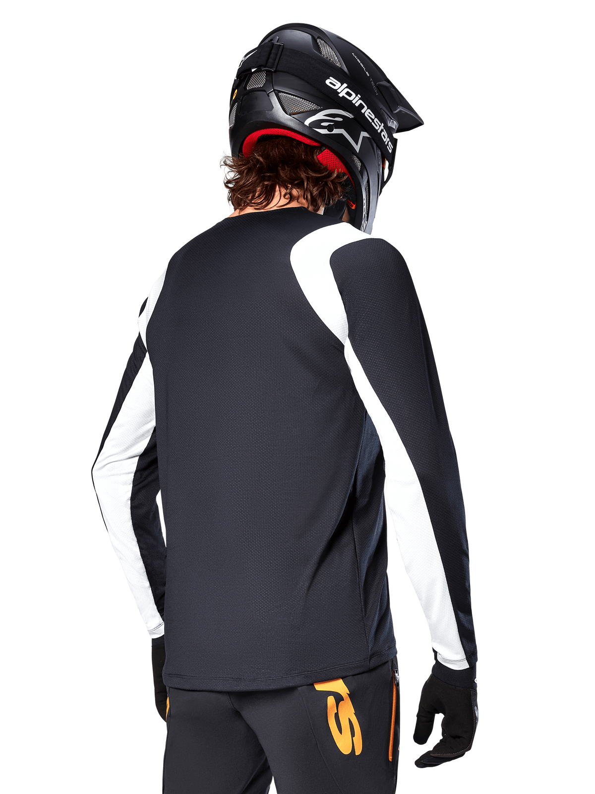 Ciclista MTB con maglia a maniche lunghe Alpinestars A-Supra Oscar, nero con pannelli bianchi sulle spalle e sulle maniche, vista posteriore, casco e guanti neri, pantaloni con accenti arancioni, abbigliamento da ciclismo fuoristrada resistente