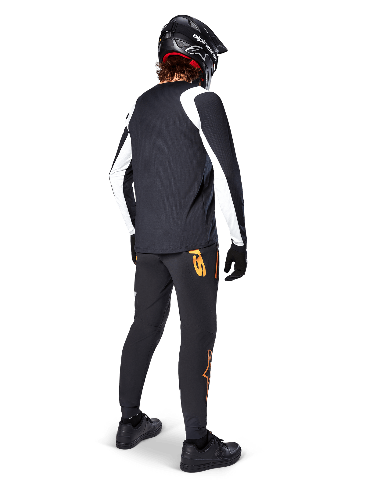 Maglia a maniche lunghe Alpinestars A-Supra Oscar, nera con pannelli bianchi sulle maniche, indossata da un rider MTB vista dal retro con casco integrale nero e pantaloni neri con loghi arancioni, abbigliamento da ciclismo per gravity off-road