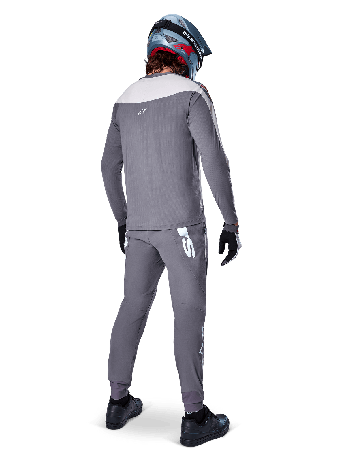Alpinestars A-Supra Race Jersey, maglia MTB a maniche lunghe, grigio scuro con inserto sulle spalle grigio chiaro, vista posteriore indossata con pantaloni coordinati, casco integrale blu e rosso, guanti e scarpe neri, abbigliamento da ciclismo tecnico ispirato alle corse