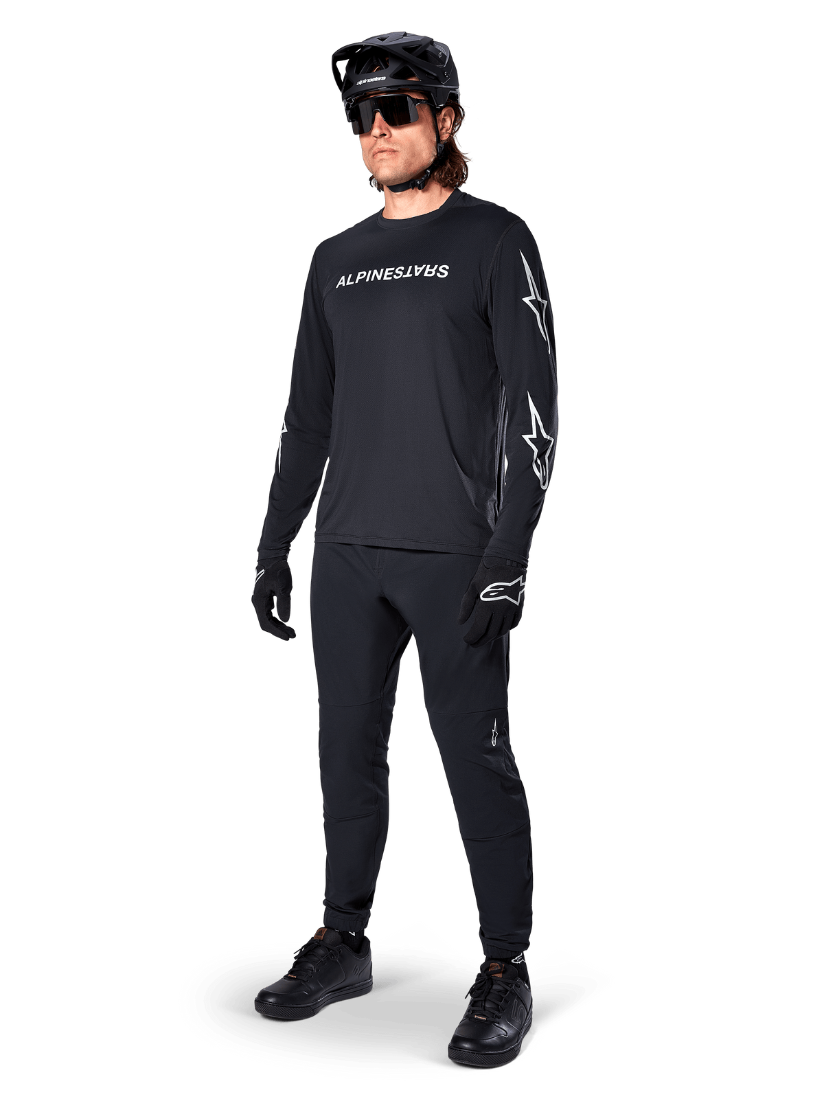 Maglia a maniche lunghe Alpinestars A-Dura Switch, nero, maglia da mountain bike indossata con pantaloni neri, casco e guanti, con logo wordmark bianco sul petto e loghi a stella sulle maniche, equipaggiamento MTB coordinato per la guida fuoristrada