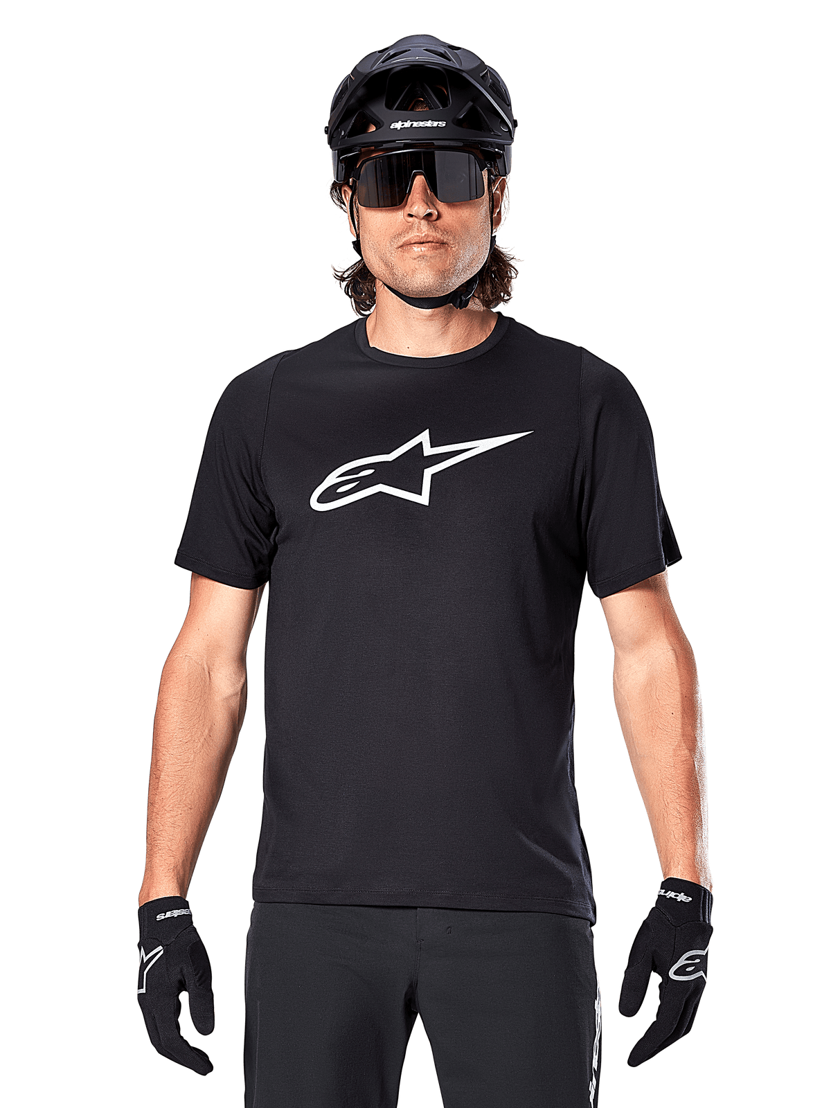 Maglia Alpinestars A-Dura Dri Oscar a maniche corte, nero riflettente, indossata con casco MTB nero, occhiali da sole e guanti, con un evidente logo bianco sul petto, abbigliamento tecnico per mountain bike