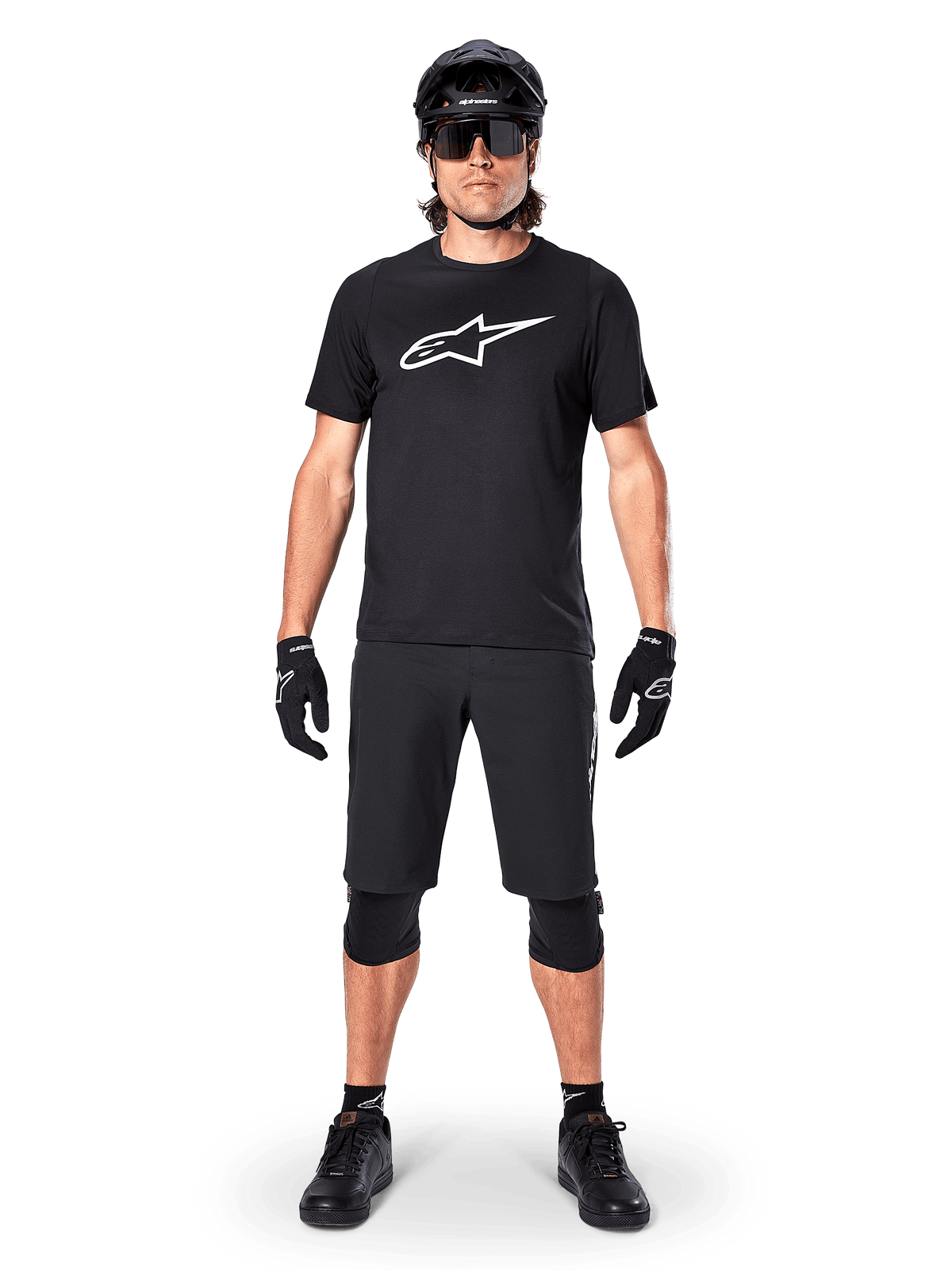 Alpinestars A-Dura Dri Oscar Short Sleeve Jersey, nero riflettente, indossata con pantaloncini da MTB neri coordinati, guanti, ginocchiere e casco, con un grande logo Alpinestars bianco sul petto, abbigliamento completo da mountain bike