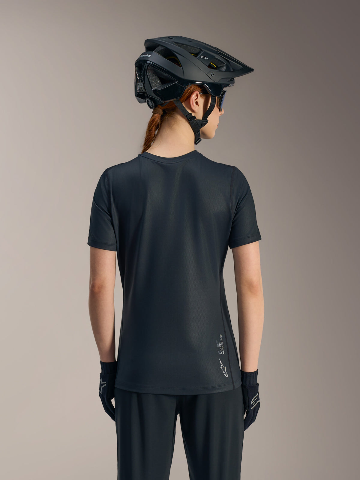 Maglia Stella A-Dura Ride nera a maniche corte da donna, vista posteriore con coda allungata e logo Alpinestars.