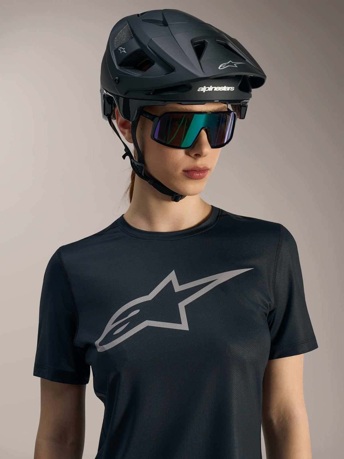 Alpinestars Stella A-Dura Ride, maglia da donna nera a maniche corte con logo grigio, casco MTB e occhiali da sole.