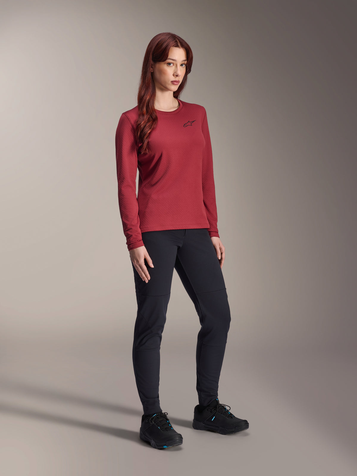 Alpinestars Stella A-Dura Thermal Jersey, maglia da mountain bike a maniche lunghe da donna, bordeaux, indossata con pantaloni sportivi neri e scarpe nere, girocollo con piccolo logo nero sul petto, design funzionale con vestibilità regolare per ciclismo off-road