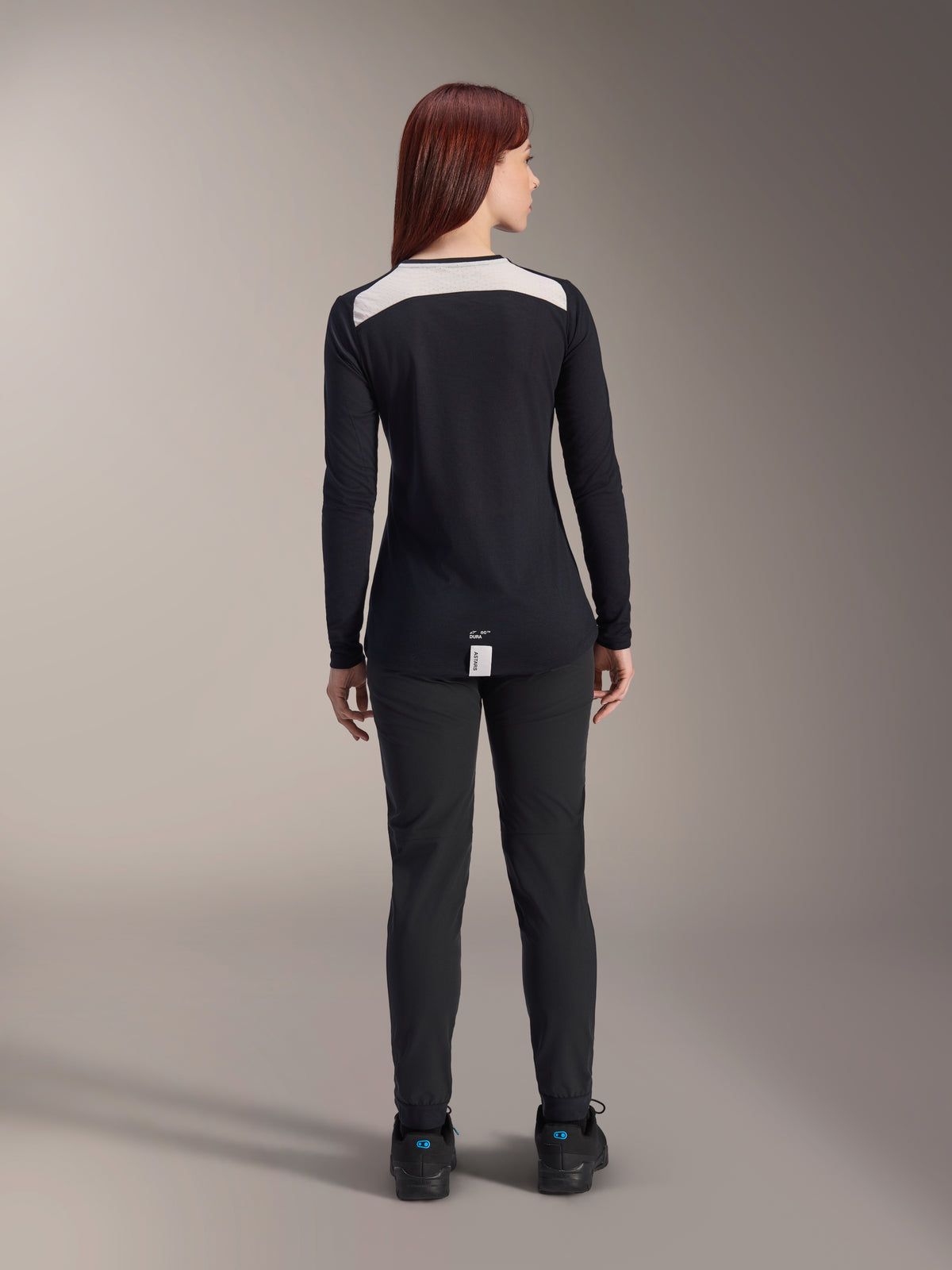 Maglia a maniche lunghe Alpinestars Stella A-Dura Dri Astar, maglia da MTB da donna nera, vista posteriore con pannello di ventilazione in mesh bianco sulle spalle, abbinata a pantaloni da ciclismo neri, abbigliamento tecnico da fuoristrada