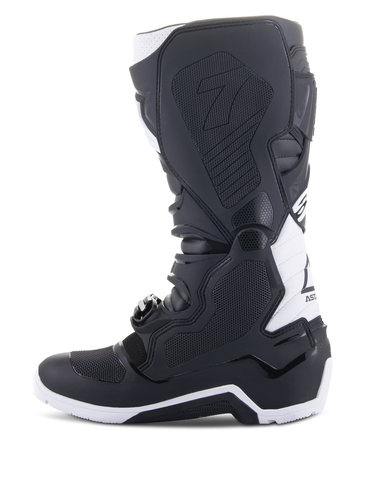 Stivali Alpinestars Tech 7 Enduro Drystar®, stivali da moto enduro, nero e bianco, vista laterale mediale con pannelli grip con trama a nido d'ape, costruzione in TPU e accenti bianchi sul tallone e sulla parte superiore del polpaccio, calzatura professionale da fuoristrada
