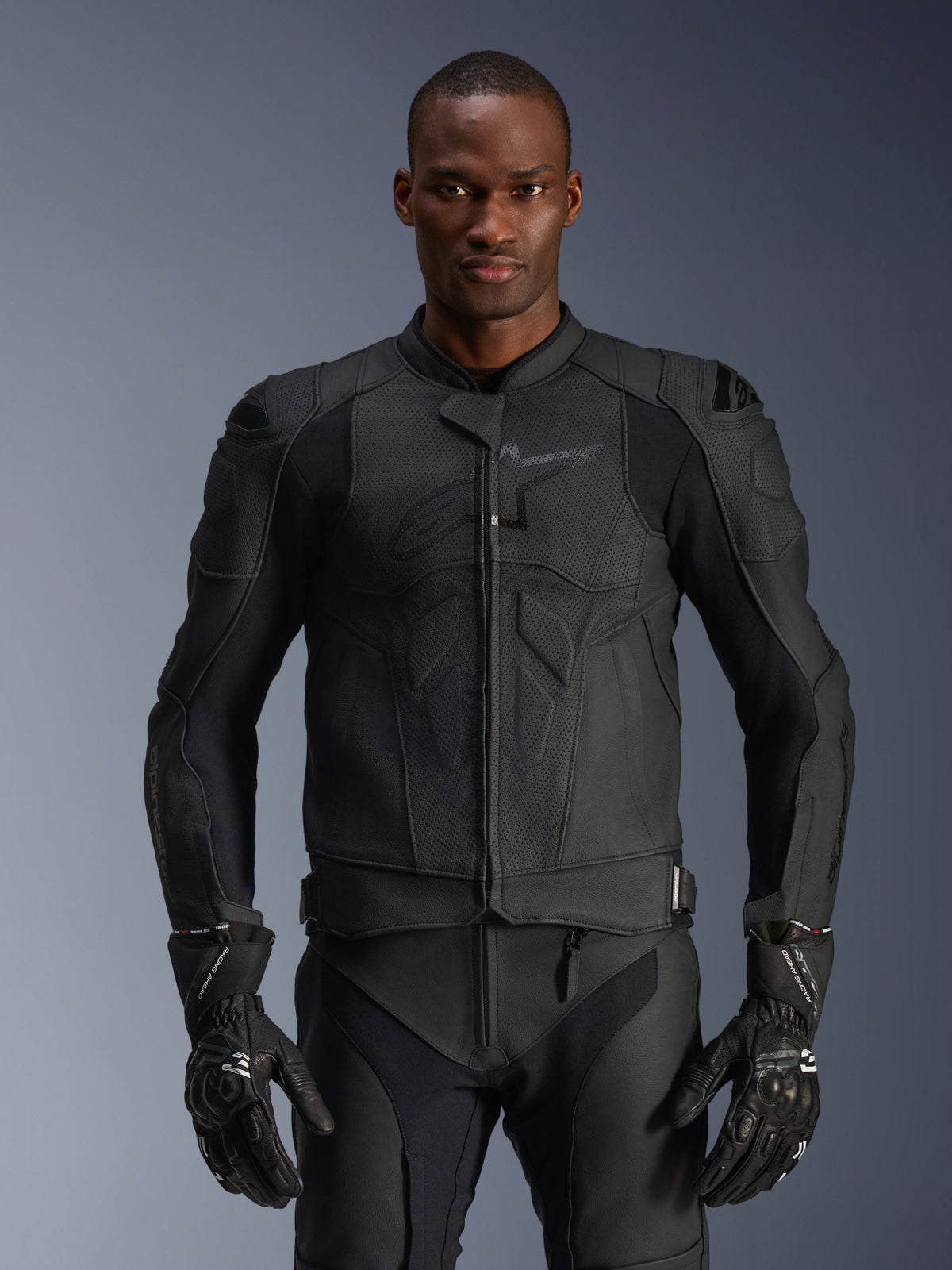 Alpinestars Dusk Airflow Leather Jacket, giacca da moto in pelle nera, pelle traforata con imbottiture protettive sulle spalle, design aderente, indossata con guanti protettivi neri coordinati