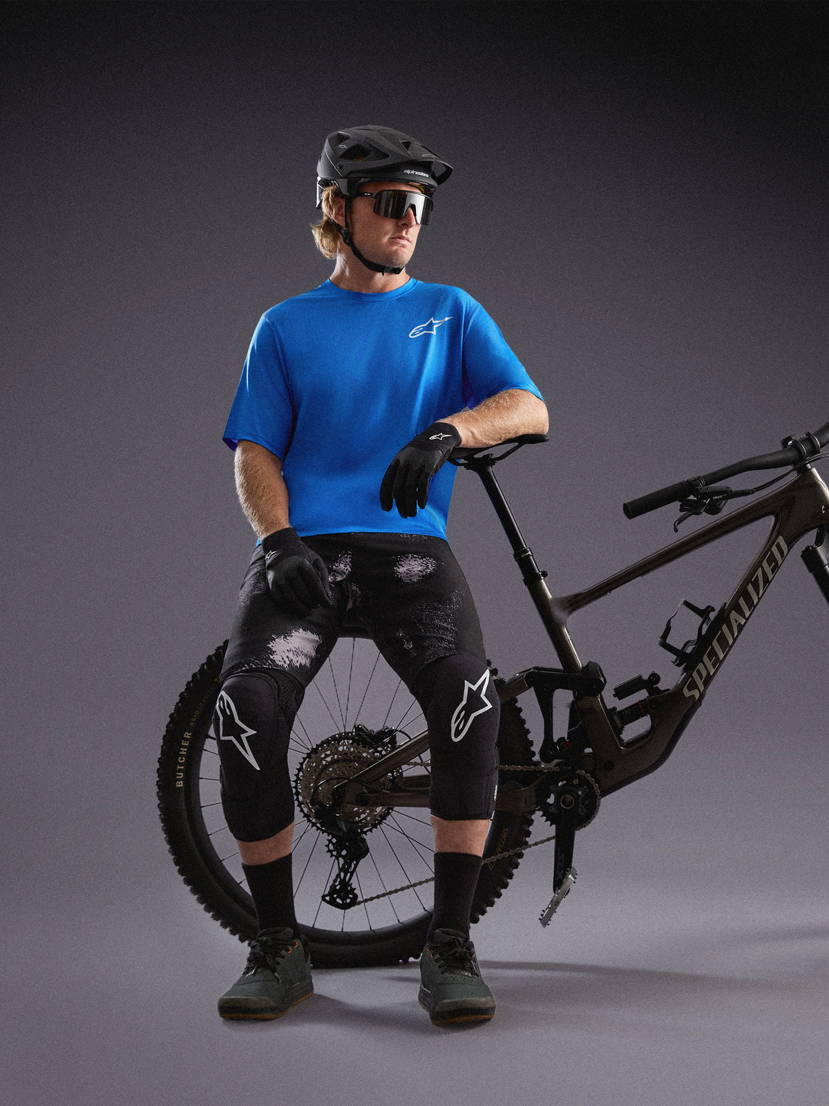Maglia Alpinestars A-Dura Air SS blu e pantaloncini Ride Black Camo indossati da un ciclista con mountain bike.