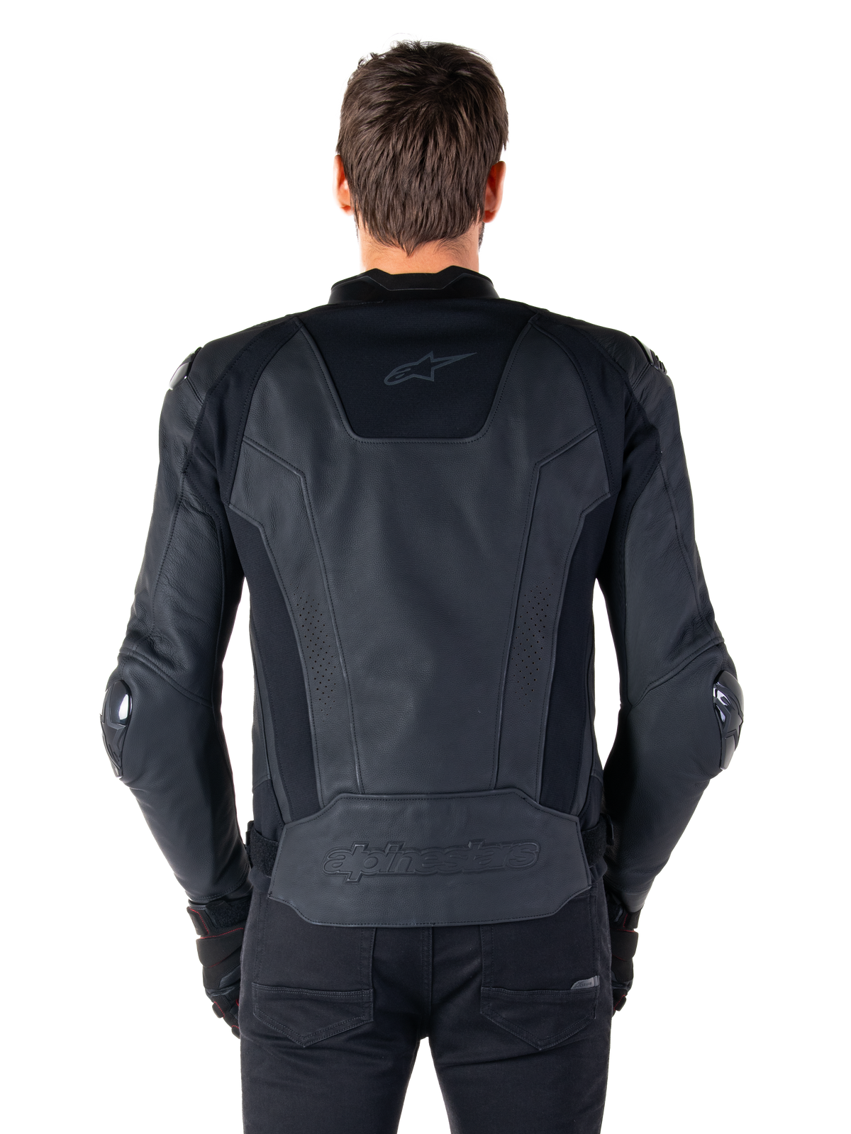 Vista posteriore di un pilota che indossa la giacca in pelle Alpinestars Missile V3 in nero, caratterizzata da una struttura in pelle pregiata con inserti tecnici elasticizzati, logo Alpinestars in rilievo sulla parte bassa della schiena e branding discreto sulla parte superiore, abbinata a pantaloni neri per un look sportivo da corsa coordinato.