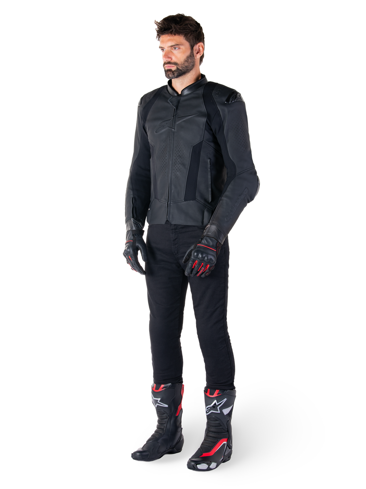 Giacca in pelle Alpinestars Missile V3, nero, indossata da un pilota con pantaloni neri e guanti e stivali da corsa neri e rossi, con pannelli in pelle traforata e branding monocromatico, estetica racing professionale