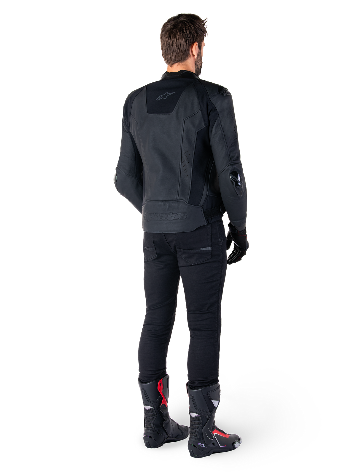 Alpinestars Missile V3 Leather Jacket in nero, vista posteriore su un pilota, indossata con pantaloni neri e stivali da corsa neri e rossi, caratterizzata da una struttura in pelle con branding tono su tono e vestibilità racing performante