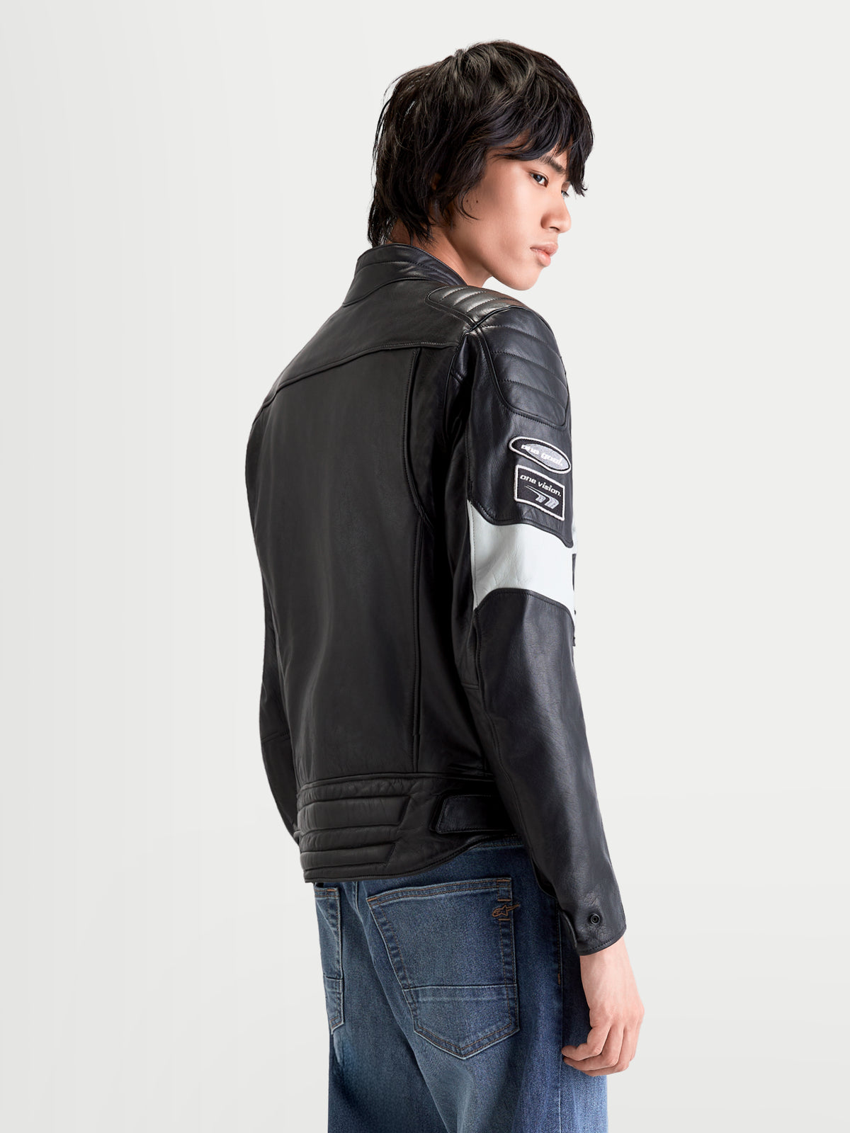 Alpinestars Revern Giacca di pelle, giacca da moto urbana da uomo in nero e grigio metallizzato, vista posteriore su un modello che indossa pelle bovina pieno fiore con dettagli racing e struttura protettiva