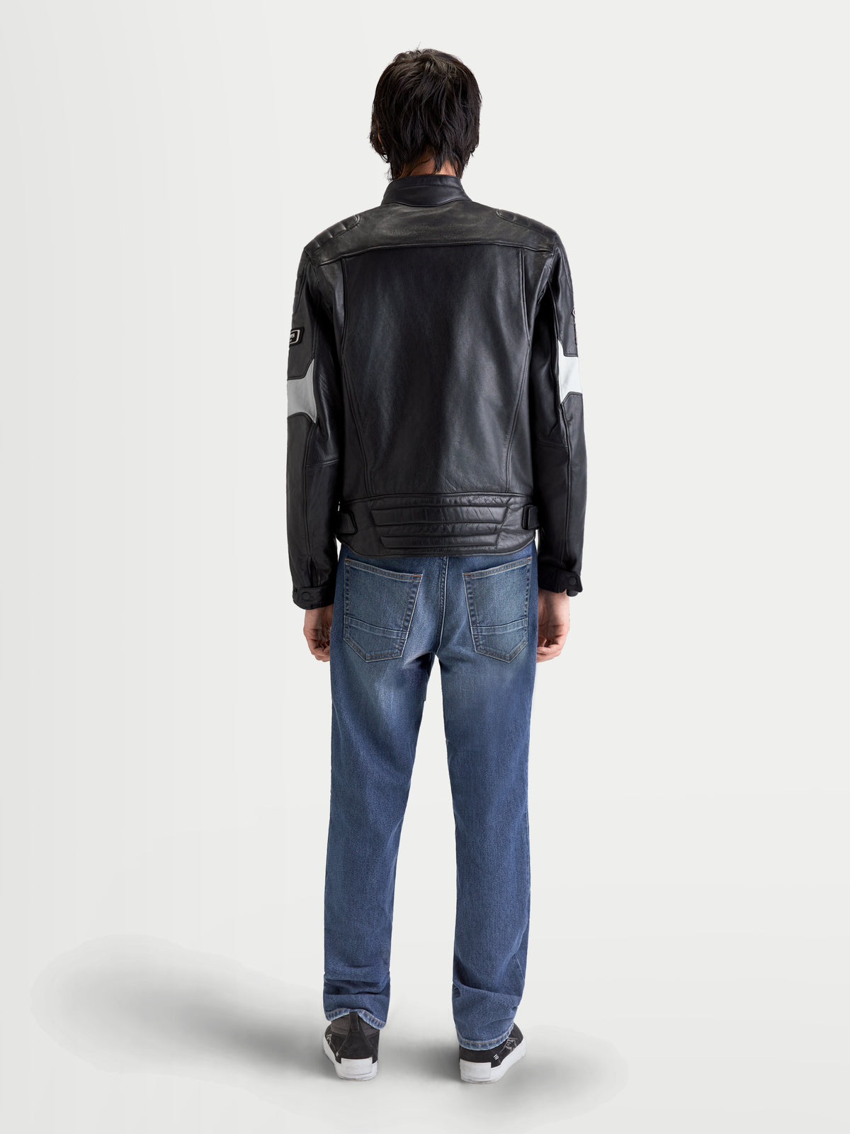 Alpinestars Revern Giacca di pelle, giacca da moto urbana da uomo in nero e grigio metal, vista posteriore su un modello che indossa jeans
