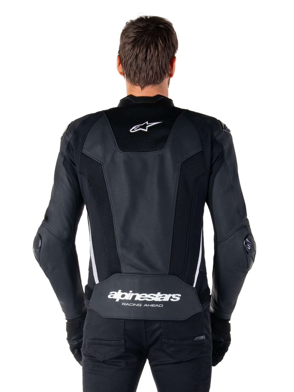 Giacca in pelle Alpinestars Missile V3 Airflow, nero e bianco, vista posteriore indossata da un pilota, con ampi pannelli in pelle traforata, accenti laterali bianchi, logo a stella Alpinestars sulla parte superiore della schiena e marchio 'alpinestars RACING AHEAD' sulla parte inferiore della schiena.