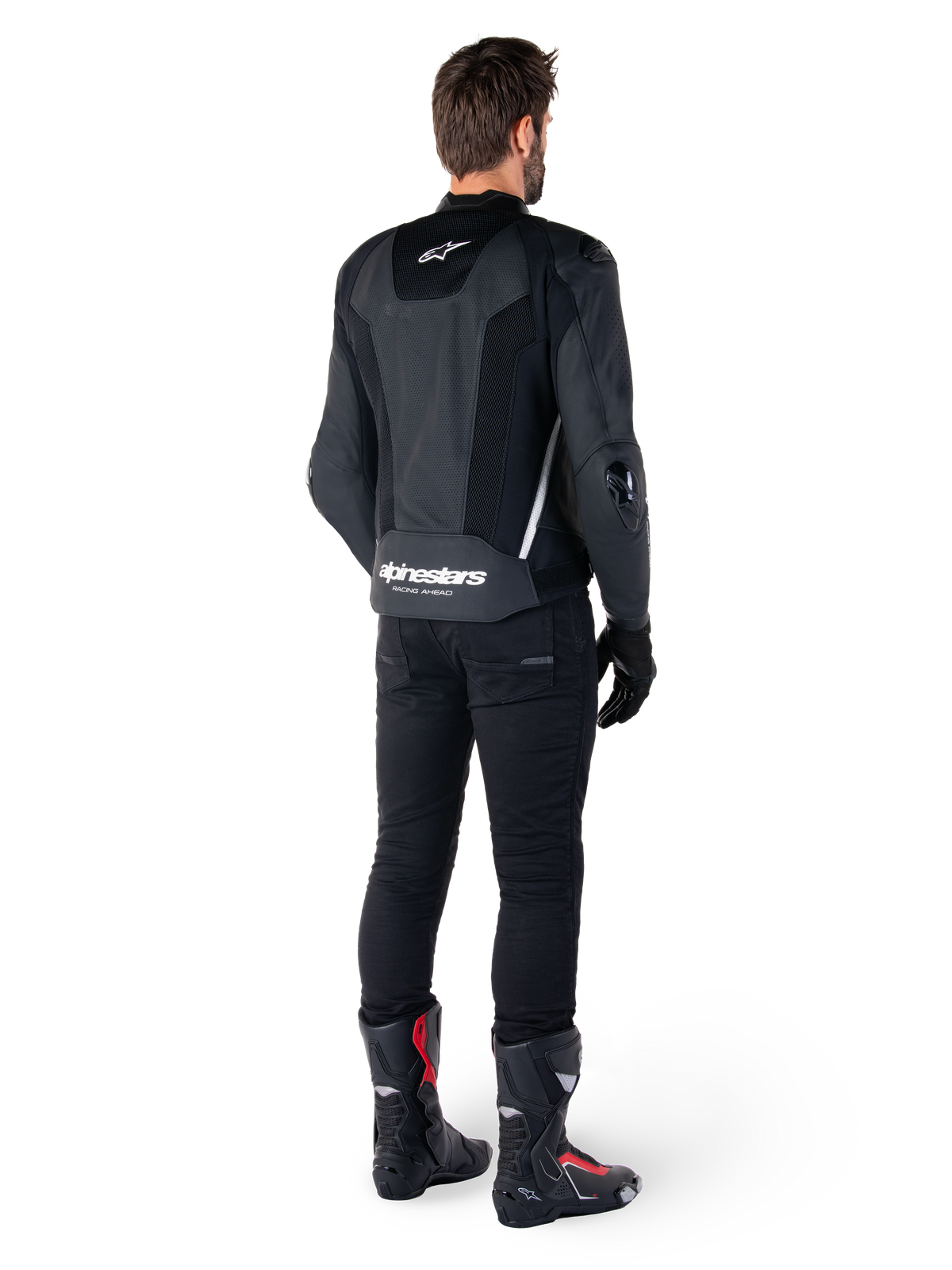 Alpinestars Missile V3 Airflow Leather Jacket, nero e bianco, vista posteriore indossata con pantaloni tecnici neri e stivali da corsa, caratterizzata da pannelli posteriori in pelle traforata e logo Alpinestars sulla parte bassa della schiena.