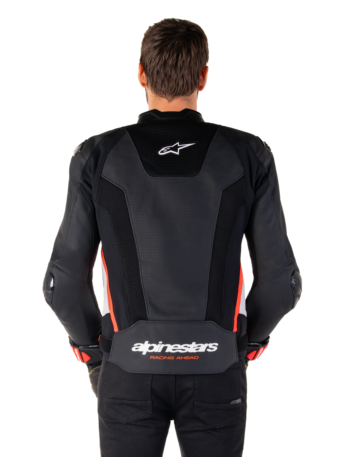 Vista posteriore di una persona che indossa la giacca in pelle Alpinestars Missile V3 Airflow in Nero Bianco Rosso Fluo, caratterizzata da ampi pannelli in pelle traforata per la ventilazione, un piccolo logo Alpinestars sulla parte superiore della schiena e il marchio 'alpinestars RACING AHEAD' sulla parte inferiore della vita.