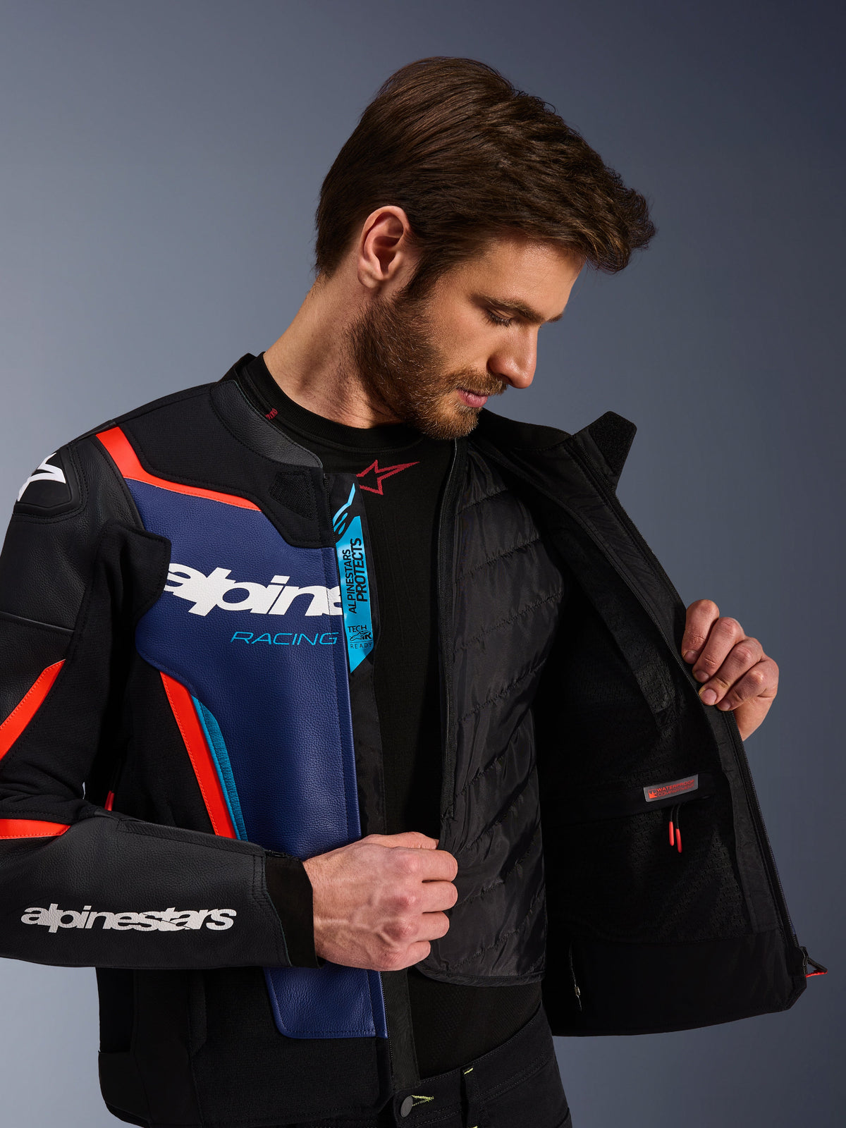 Giacca in pelle Alpinestars GP Force V2 in Nero Blu e Rosso Fluo, vista ravvicinata che mostra il gilet termico interno staccabile e la tasca impermeabile, pelle bovina premium con marchio Tech-Air Ready, abbigliamento da moto ottimizzato per lo sport