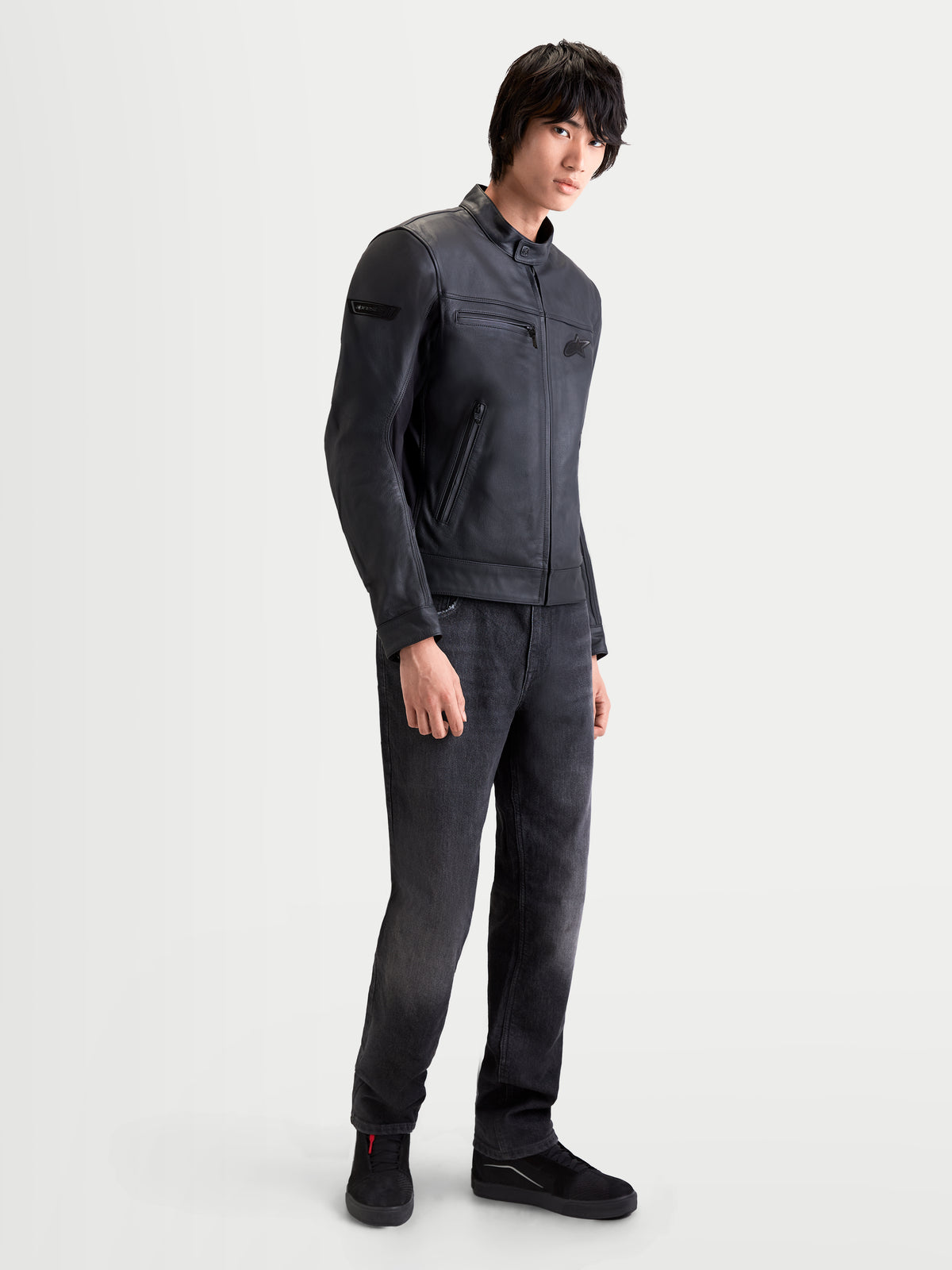 Alpinestars Maver X Giacca di pelle, giacca da moto urbana contemporanea da uomo in pelle nera, vista laterale indossata da un modello che mostra la struttura in pelle bovina pregiata e il collo alla coreana