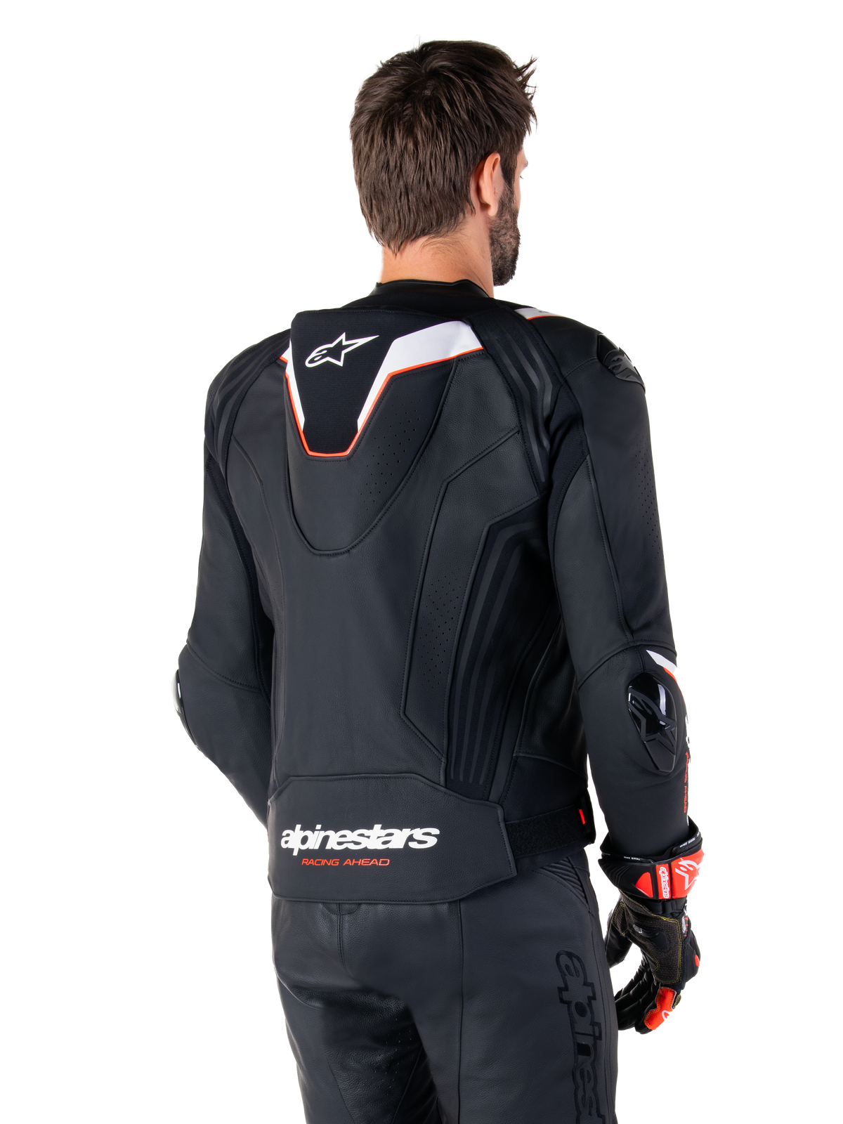 Giacca in pelle Alpinestars Missile V3 Ignition, vista posteriore, nero con accenti bianchi e rossi, con gobba aerodinamica sportiva sottile e marchio Alpinestars, indossata con pantaloni in pelle coordinati e guanti da corsa