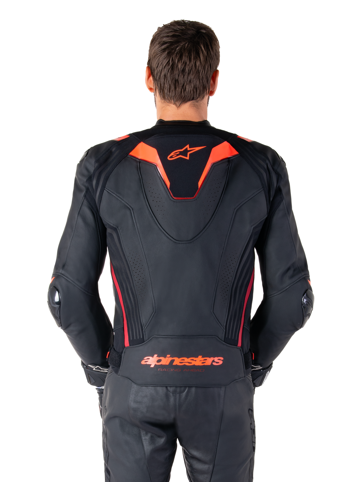 Giacca in pelle Alpinestars Missile V3 Ignition, vista posteriore, nero con accenti rosso fluo e rosso scuro, con gobba aerodinamica sportiva e logo Alpinestars sulla schiena, indossata con pantaloni coordinati in pelle nera, abbigliamento tecnico da competizione motociclistica