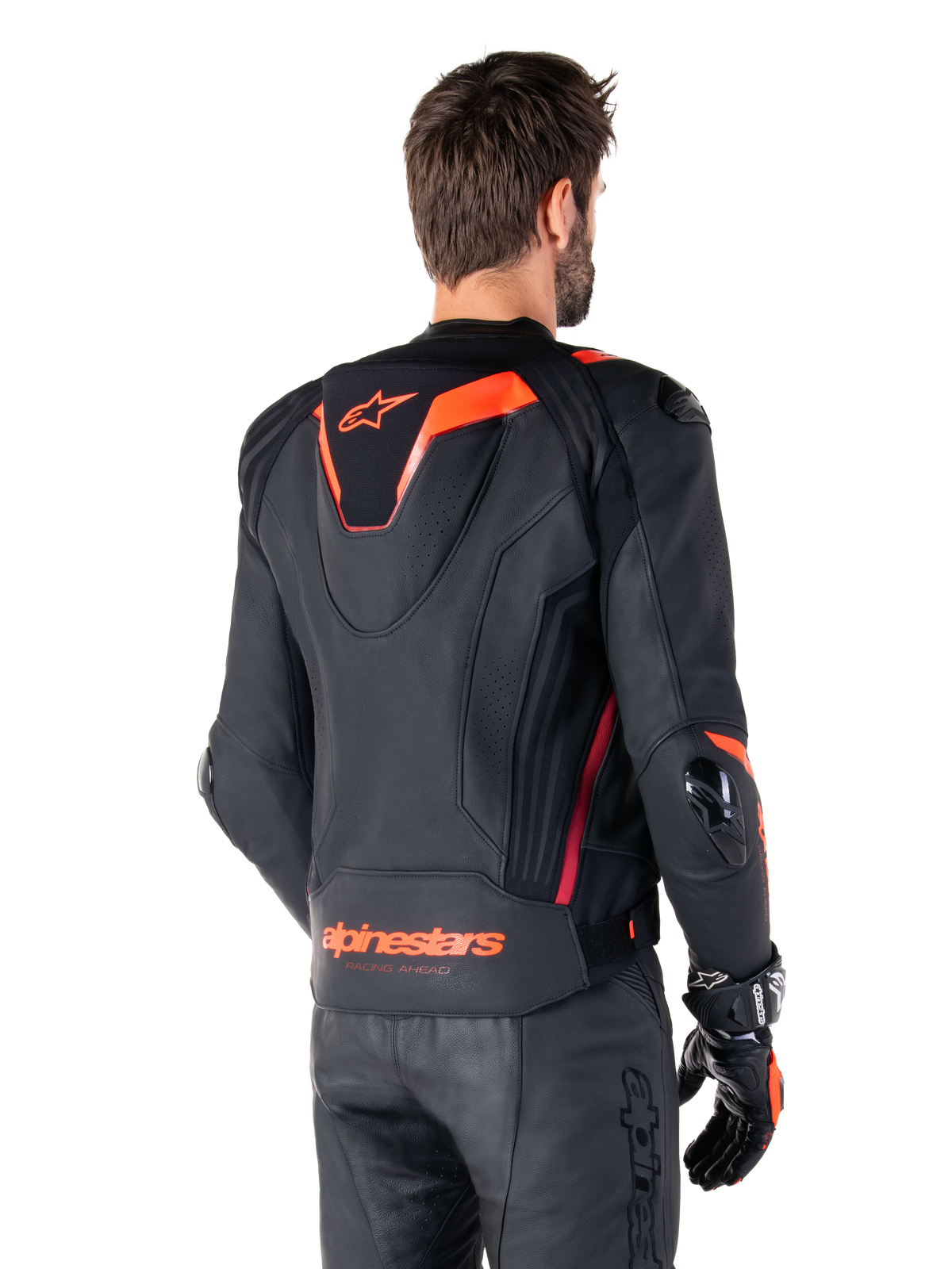 Giacca in pelle Alpinestars Missile V3 Ignition, giacca sportiva da corsa da uomo, nero con dettagli rosso fluo, vista posteriore con la sottile gobba sportiva aerodinamica e marchio Alpinestars sulla parte bassa della schiena, indossata con pantaloni in pelle neri e guanti da corsa, design motorsport professionale ed elegante