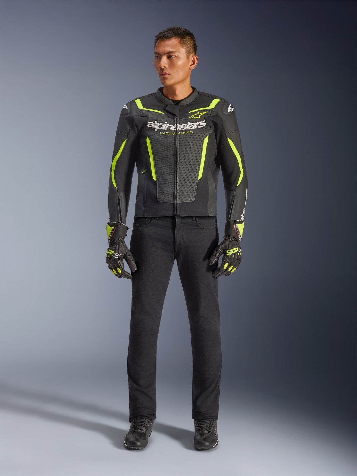 Giacca in pelle Alpinestars GP Force V2 Air, nero e giallo fluo, giacca sportiva in pelle traforata con vivaci accenti gialli e marchio Alpinestars, indossata con pantaloni neri e guanti da moto coordinati