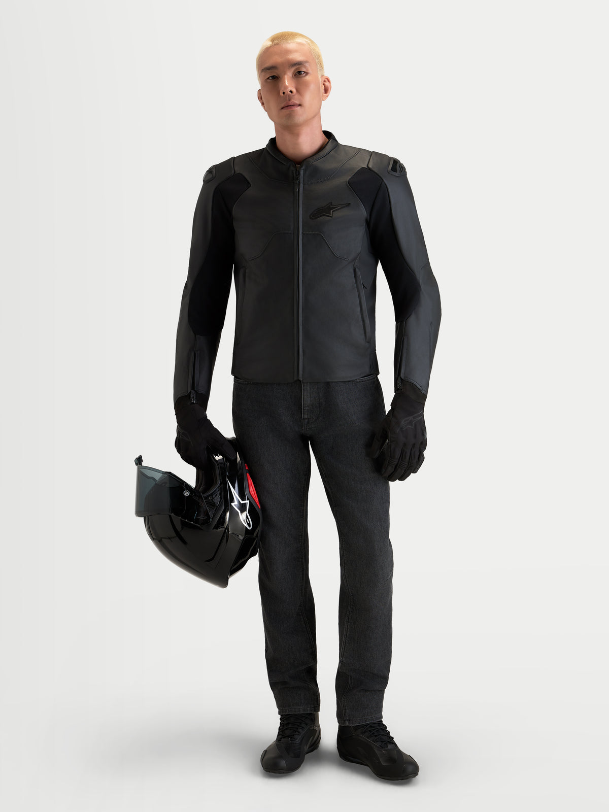 Alpinestars Caliber V2 Giacca di pelle, giacca da moto in pelle da uomo nera con protezione certificata AA, spalle DFS a basso profilo e costruzione in pelle bovina pieno fiore, indossata da un modello che tiene un casco nero