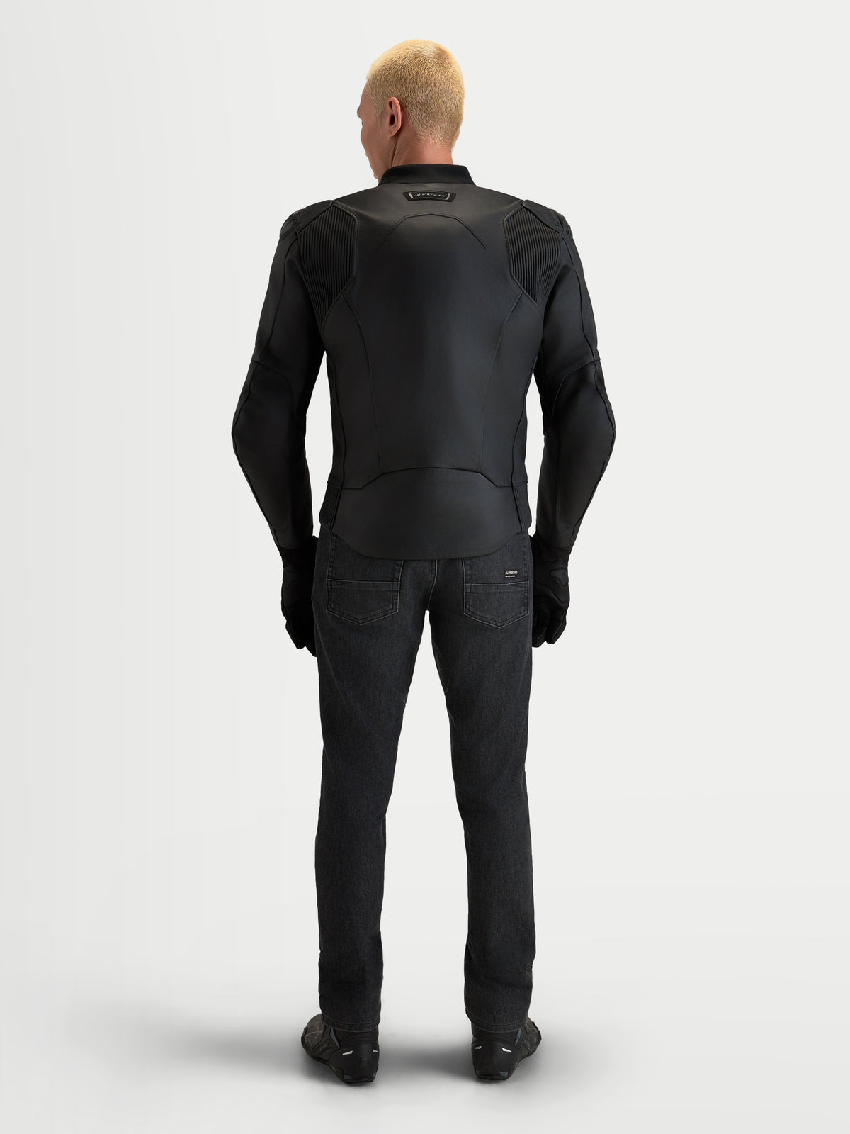 Alpinestars Caliber V 2 Giacca di pelle, giacca da moto da uomo in pelle nera, vista posteriore di un modello che indossa abbigliamento da guida sportiva