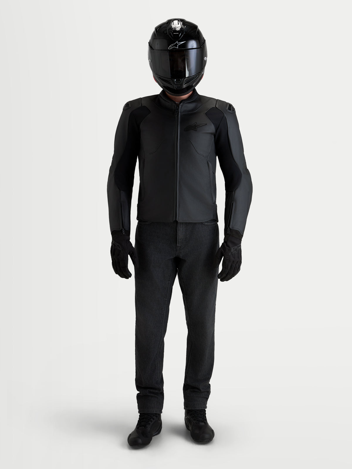 Alpinestars Caliber V 2 Giacca di pelle, giacca da moto sportiva da uomo, nera, indossata da un pilota con casco e abbigliamento coordinato