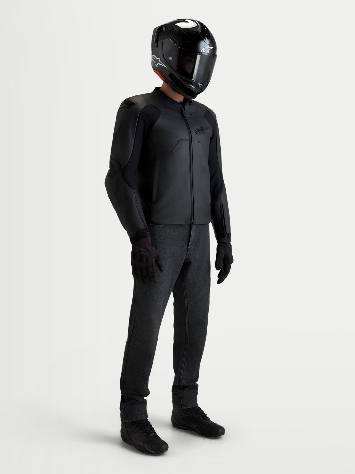 Alpinestars Caliber V2 Giacca in pelle, giacca da moto in pelle nera da uomo, indossata da un pilota con casco, pantaloni e stivali neri coordinati, con protezione di classe AA e vestibilità sportiva affusolata per la guida su strada