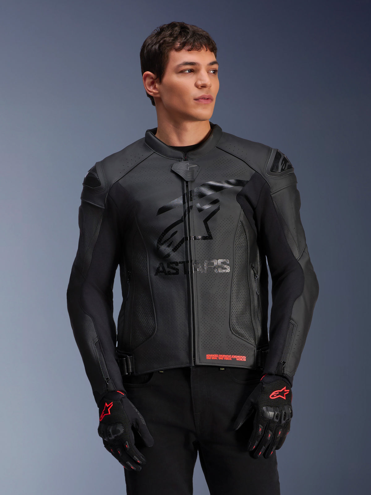 Alpinestars GP Plus R V4 Airflow Leather Jacket, giacca da moto racing in pelle nera con costruzione in pelle traforata, logo ASTARS sul petto e protezioni per le spalle DFS, indossata con guanti neri e rossi