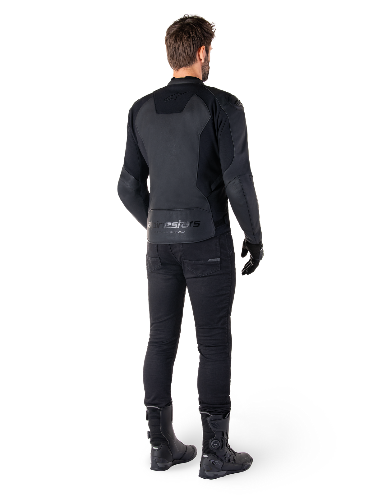 Alpinestars Faster V3 Leather Jacket, giacca in pelle da moto, nero, vista posteriore su un pilota, con pannelli in pelle pregiata e marchio Alpinestars in rilievo, abbinata a pantaloni e stivali da moto neri per un look sportivo completo.