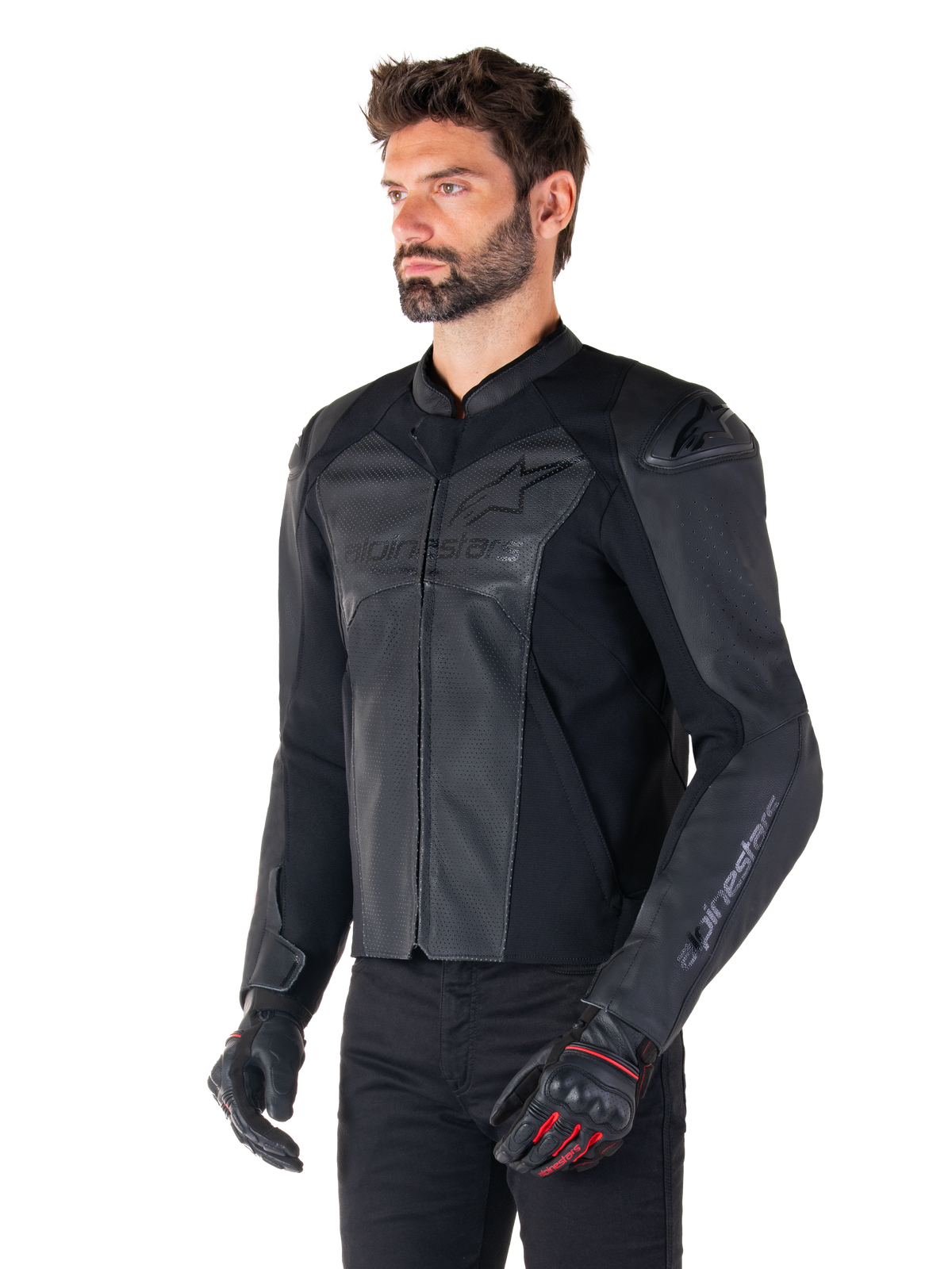 Modello che indossa la giacca in pelle Alpinestars Faster V3 Airflow in Black Black, giacca da moto sportiva con pelle traforata e pannelli elasticizzati, abbinata a pantaloni neri e guanti neri con accenti rossi, stile raffinato di derivazione racing
