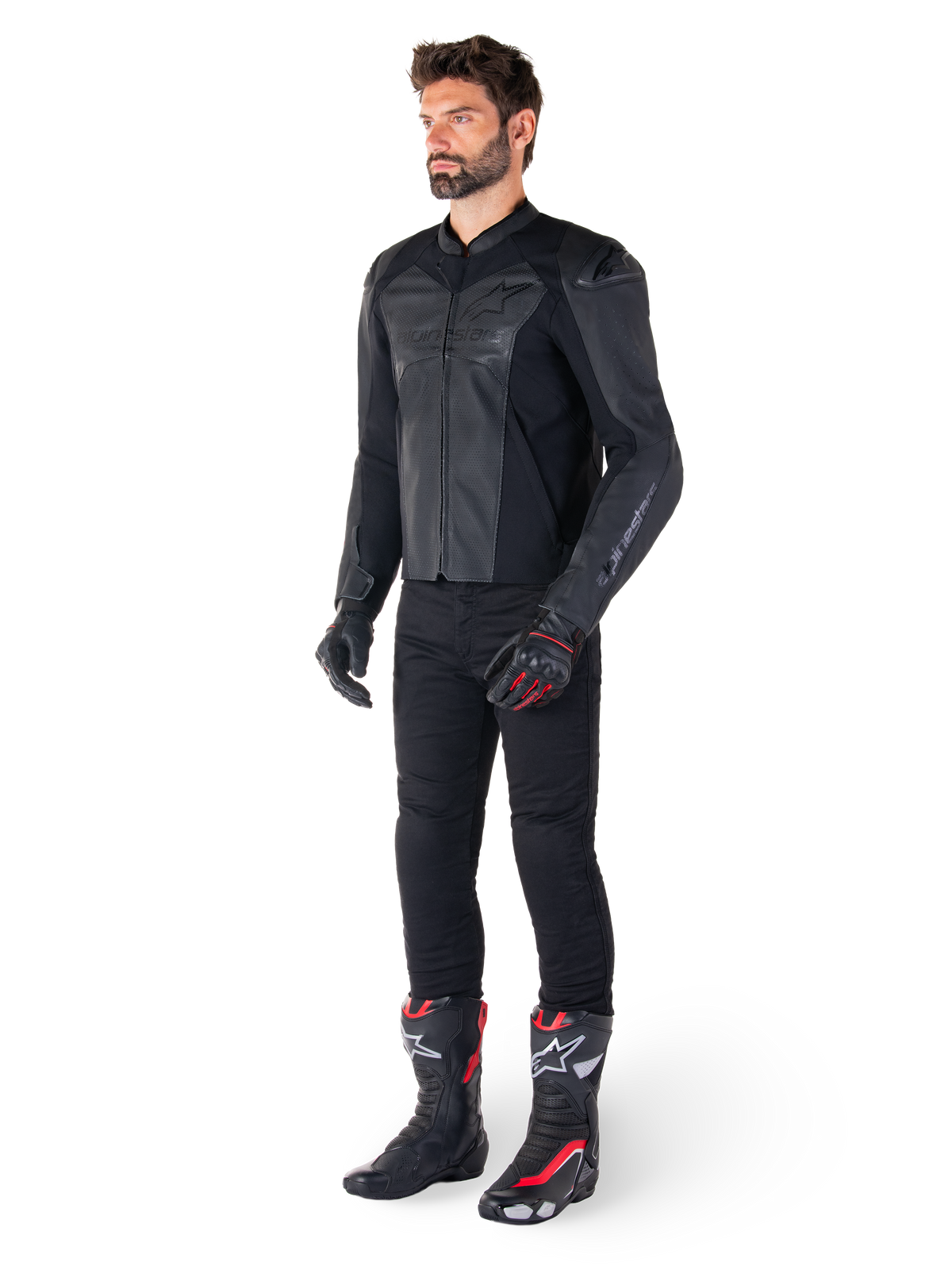 Uomo che indossa la giacca in pelle Alpinestars Faster V3 Airflow in Nero Nero, abbinata a pantaloni neri, guanti da moto neri e rossi e stivali da corsa neri con dettagli rossi e bianchi, equipaggiamento da guida sportiva completo