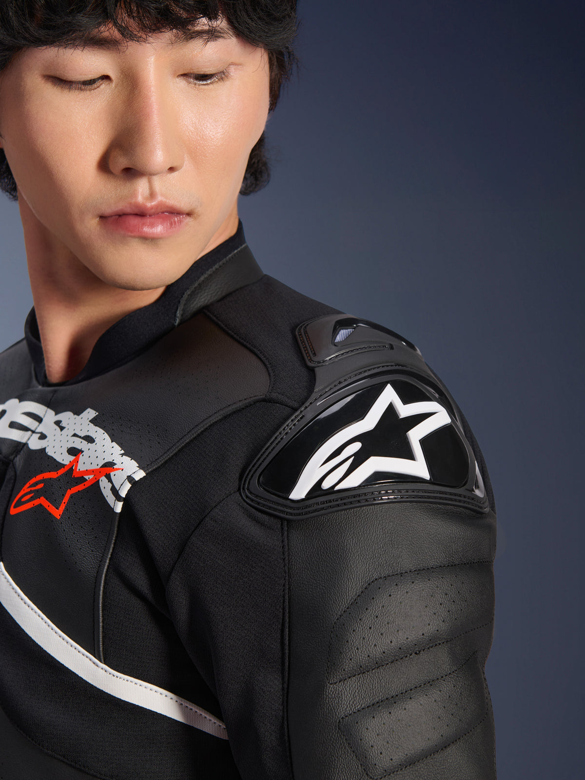Primo piano della giacca in pelle Alpinestars Atem V5 in nero e bianco, con protezione per la spalla DFS RR con logo a stella bianco, costruzione in pelle traforata e grafiche sul petto ispirate alle corse.
