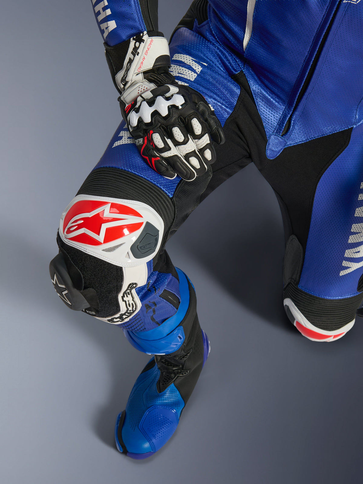 Tuta intera in pelle Alpinestars Yamaha GP-R7, tuta da moto, blu metallizzato e nero, con logo Alpinestars bianco e rosso sulla protezione del ginocchio, slider ginocchio GP sostituibile e stivale da corsa blu coordinato, equipaggiamento professionale pronto per la pista