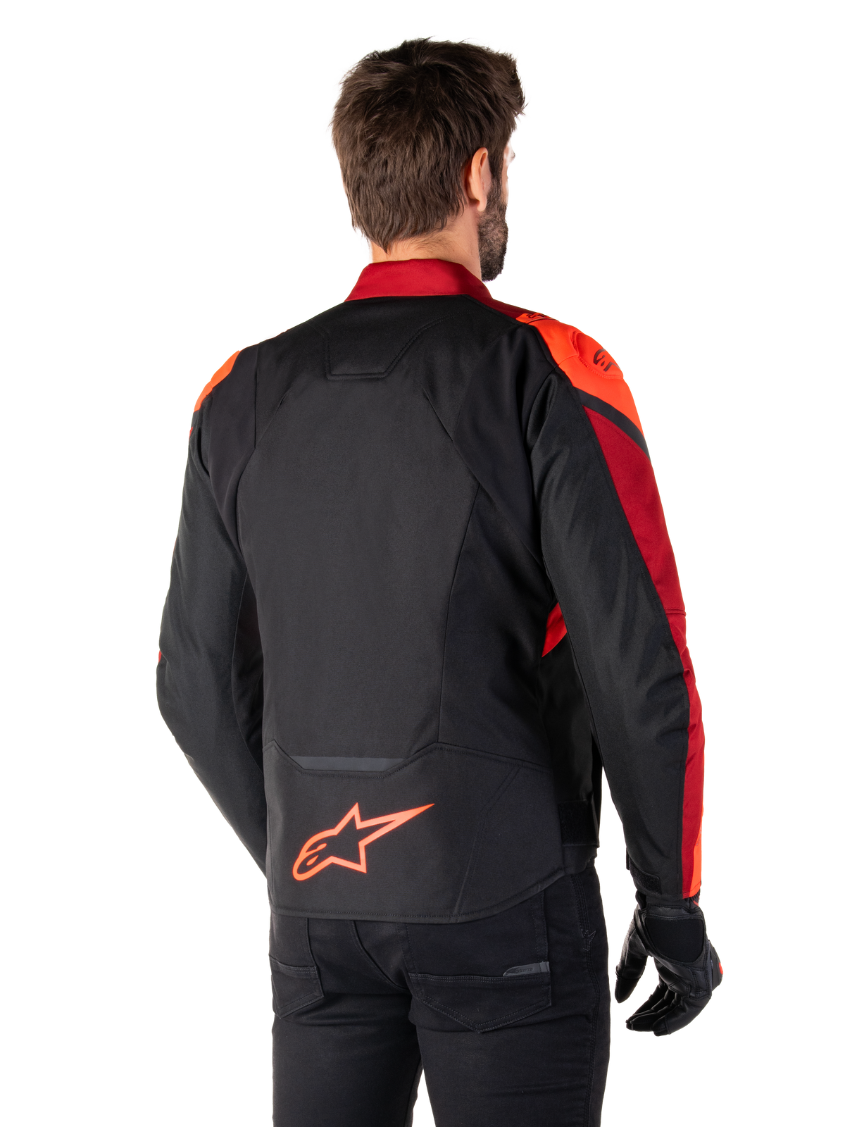 Vista posteriore di un uomo che indossa la giacca Alpinestars T-Jaws V4 Waterproof in Black Red Fluo Dark Red, con vivaci accenti rossi su spalle e maniche, logo Alpinestars rosso fluo sulla parte bassa della schiena, abbinata a pantaloni e guanti neri